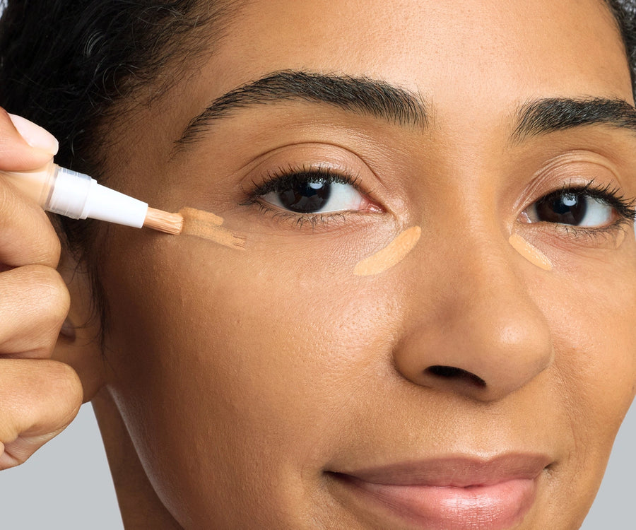 Close up of a person applying concealer to their under eye area